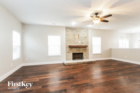 A spacious room with a fireplace and wooden floors.