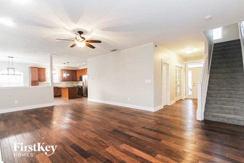 A spacious room with wooden floors and a ceiling fan.