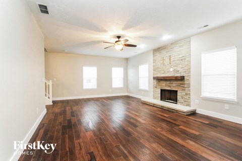 A room with wooden floors and a stone fireplace.