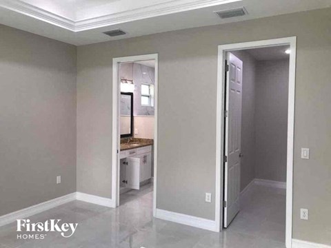 A room with a kitchen in the background and a doorway leading to another room.