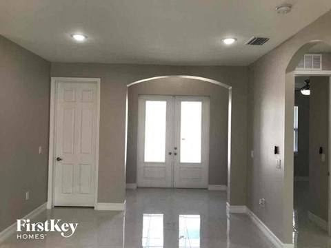 A spacious room with a white door and a large arched window.