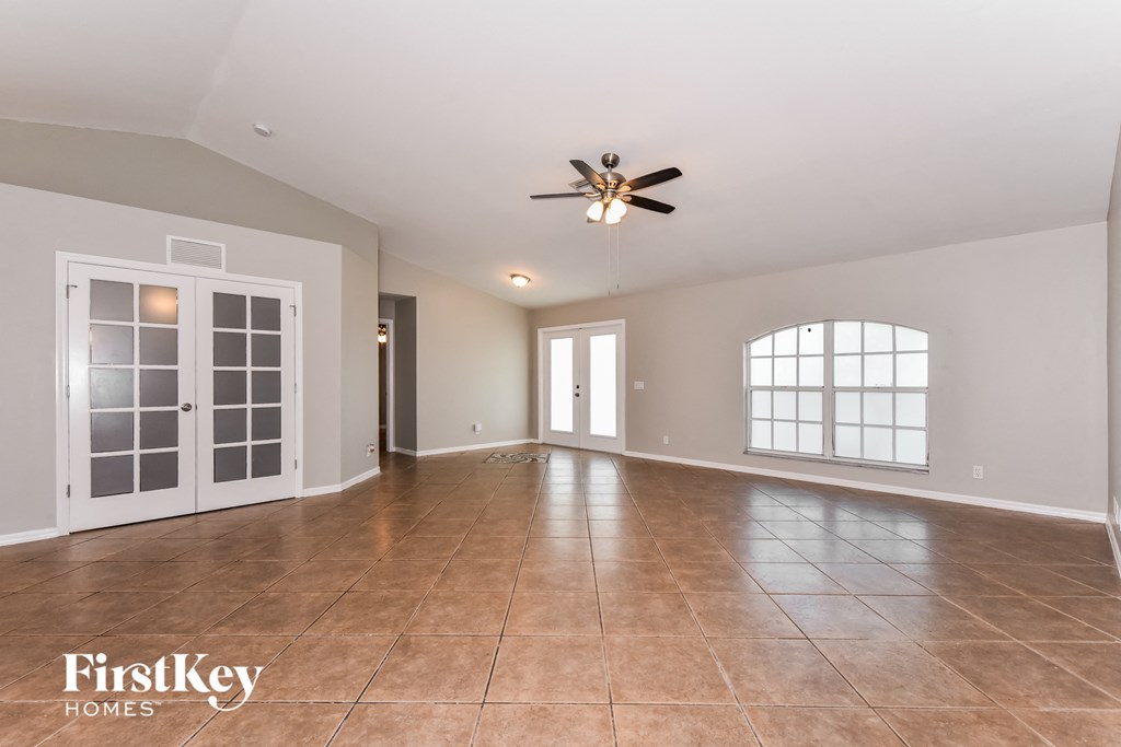 an empty living room with a ceiling fan and a large window