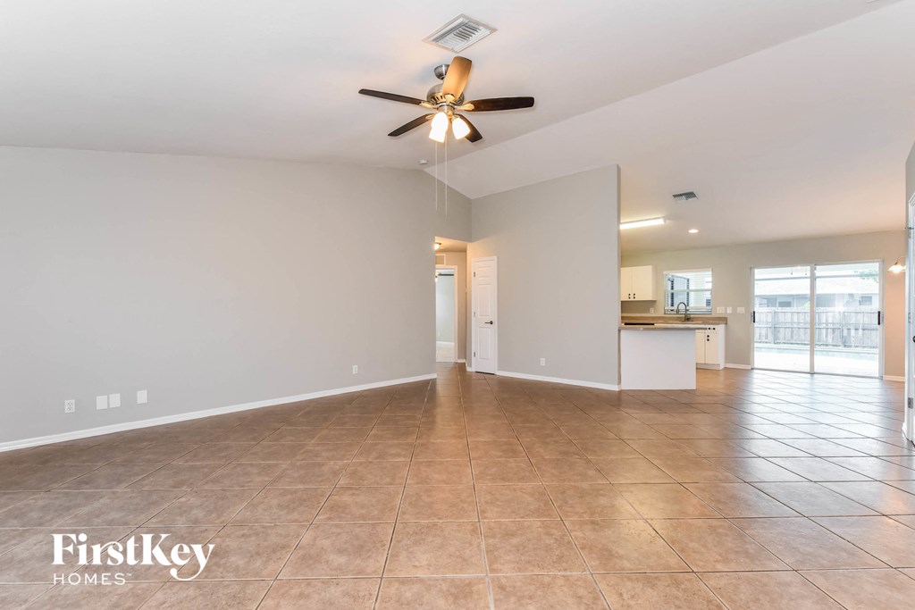 a spacious living room with a ceiling fan and tile flooring