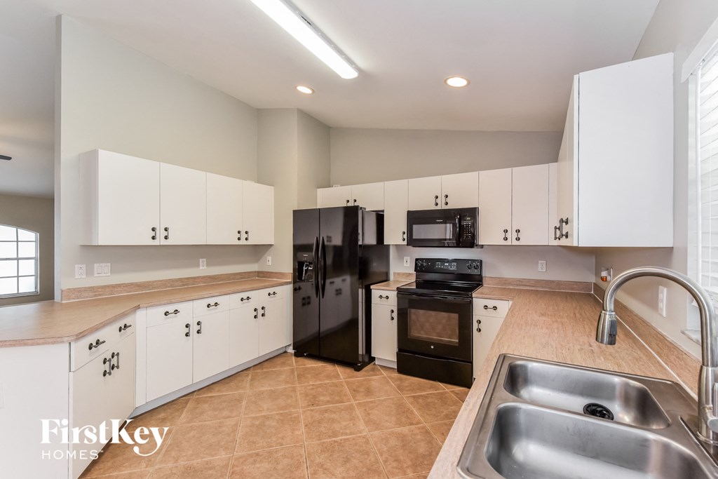 a large kitchen with white cabinets and black appliances