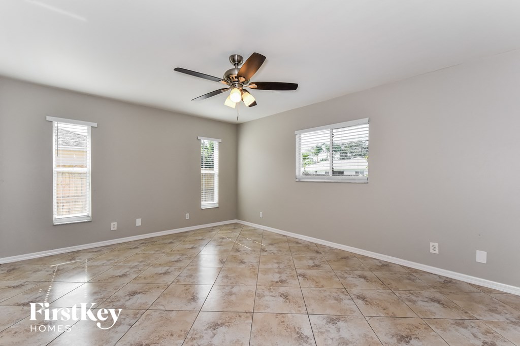 an empty living room with a ceiling fan and tile floors