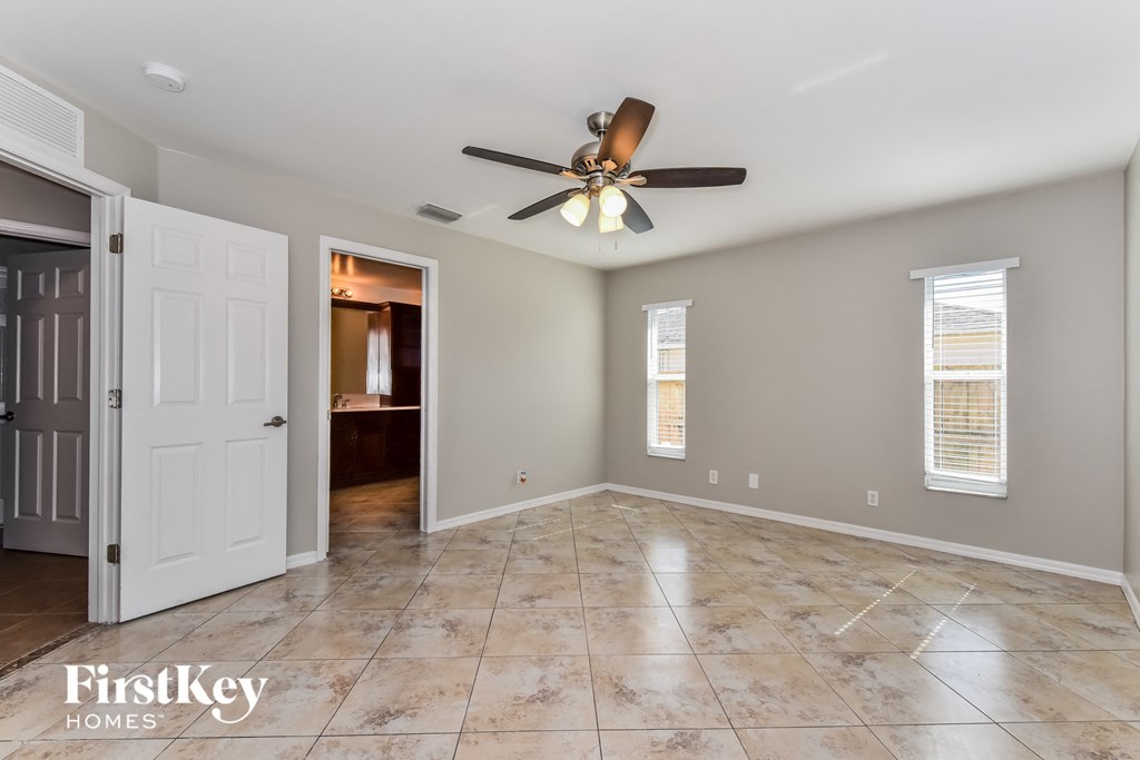 an empty living room with a ceiling fan and a door to a bathroom