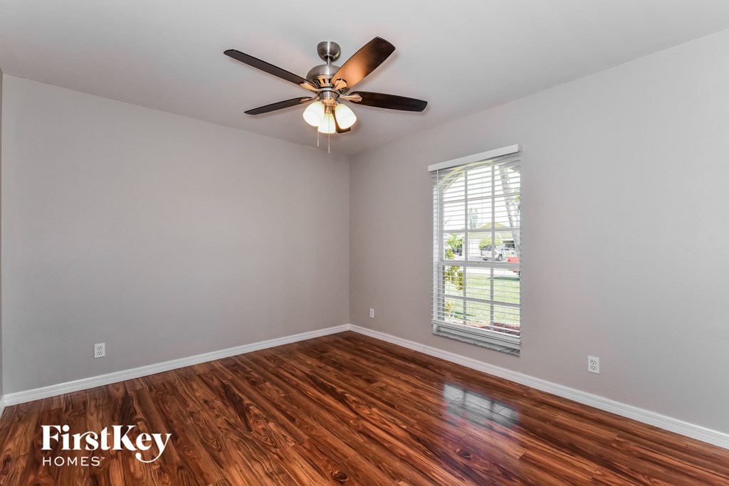 the living room with wood floors and a ceiling fan