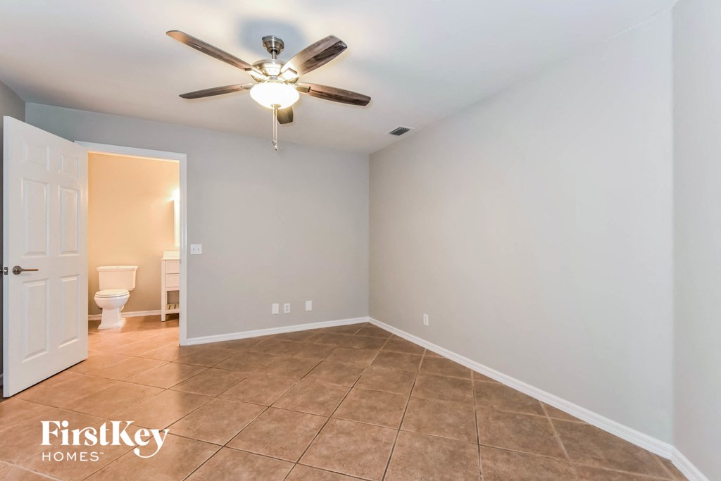 a clean and empty room with a ceiling fan and a toilet