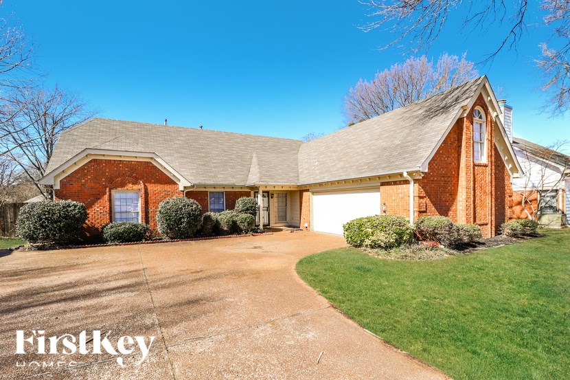 A brick house with a garage and a driveway in front.