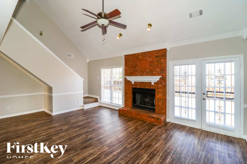 A spacious living room with a fireplace and a ceiling fan.