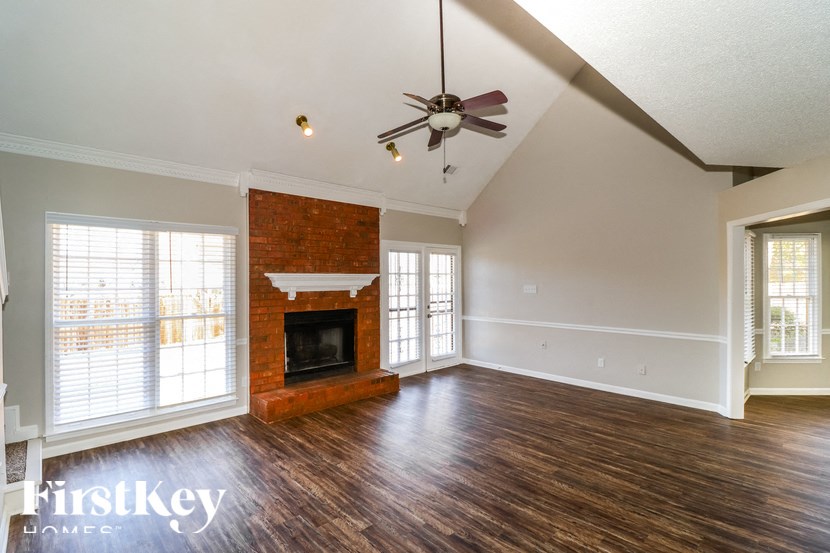 A large empty room with a fireplace and a fan.