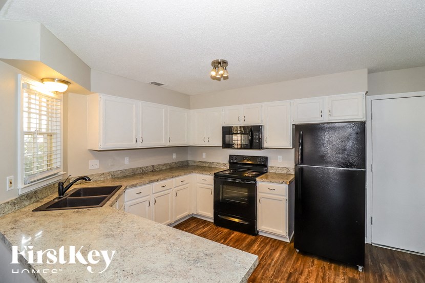 A kitchen with a black refrigerator and white cabinets.