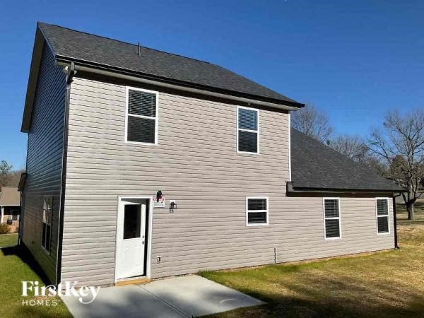 a white barn with a white house and a blue sky