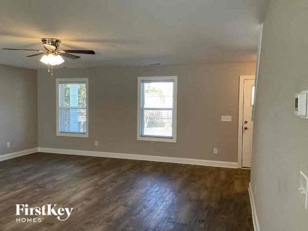 an empty living room with a ceiling fan and a window