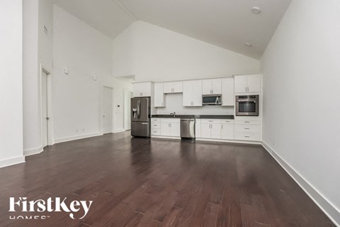 A kitchen with white cabinets and a dark wood floor.