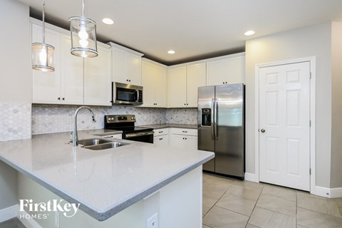 A modern kitchen with a stainless steel refrigerator and a marble countertop.