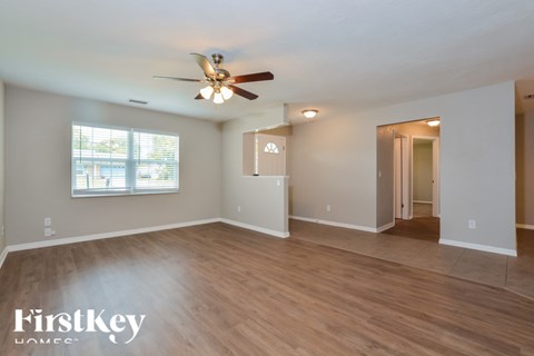 A spacious room with a ceiling fan and wooden flooring.