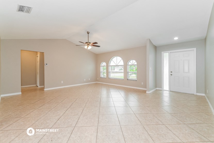 the spacious living room with tile flooring and a ceiling fan