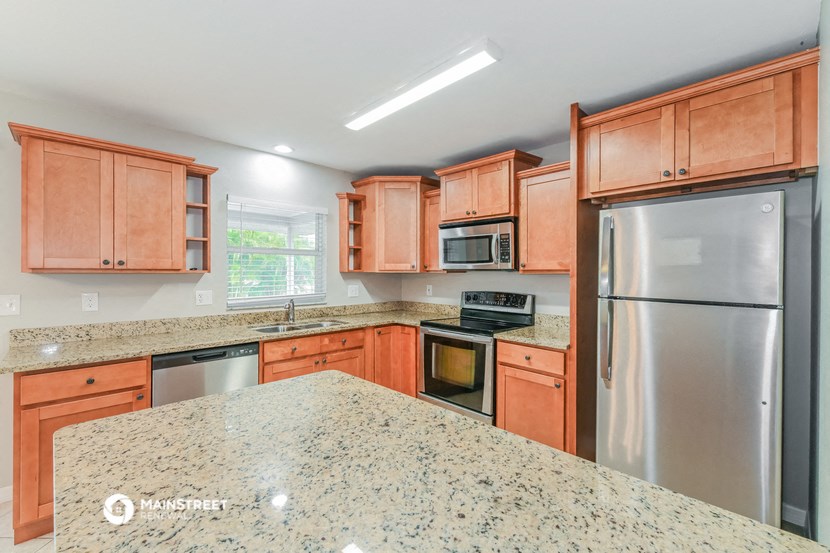 an updated kitchen with granite countertops and wooden cabinets and stainless steel appliances