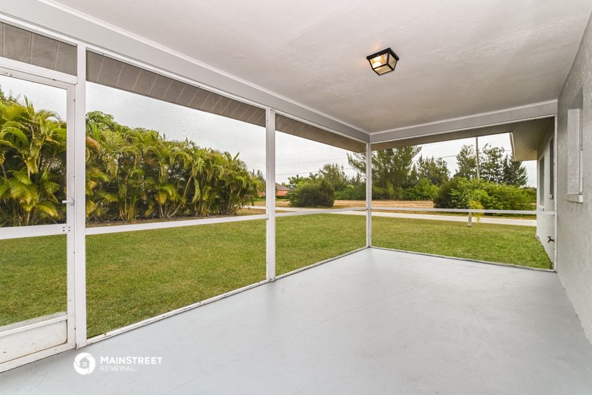 a large porch with a grassy yard and a glass sliding door