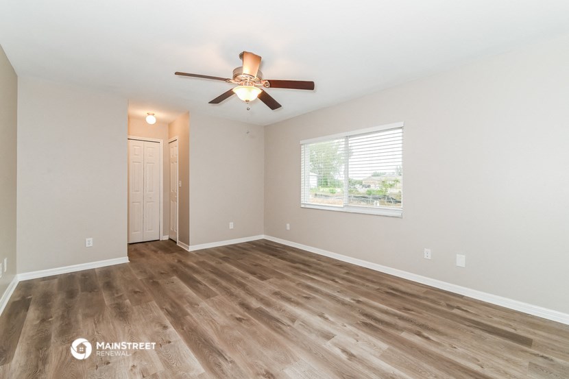 the spacious living room with wood flooring and a ceiling fan