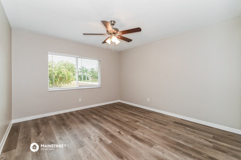 the spacious living room with hardwood floors and a ceiling fan