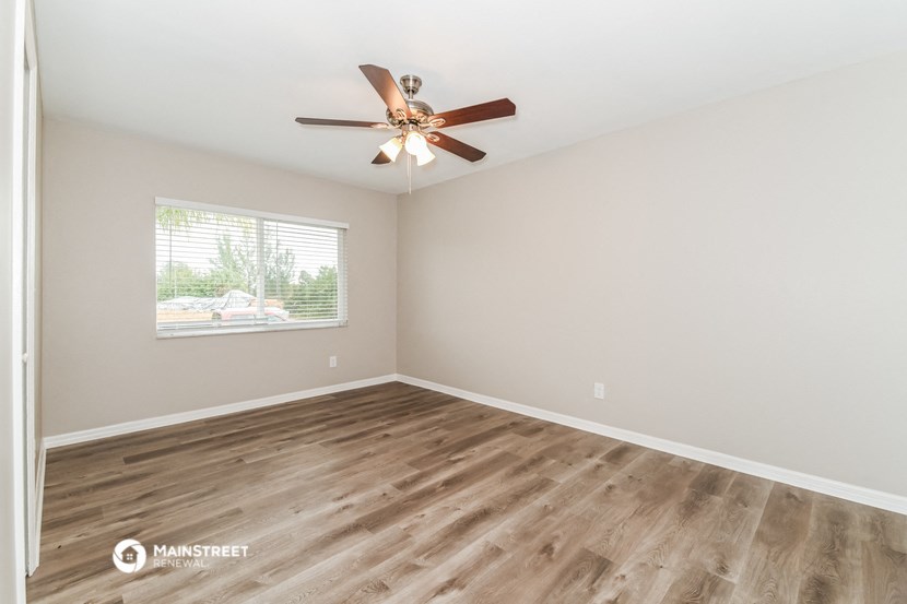 the spacious living room with hardwood floors and a ceiling fan