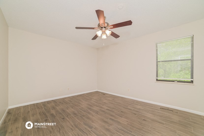 the spacious living room with ceiling fan and wood flooring