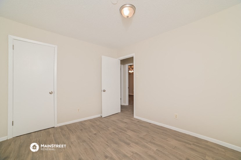 a spacious living room with white walls and wood flooring
