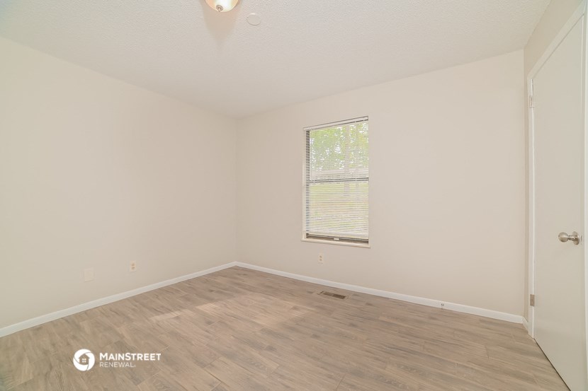 a spacious living room with wood flooring and a window