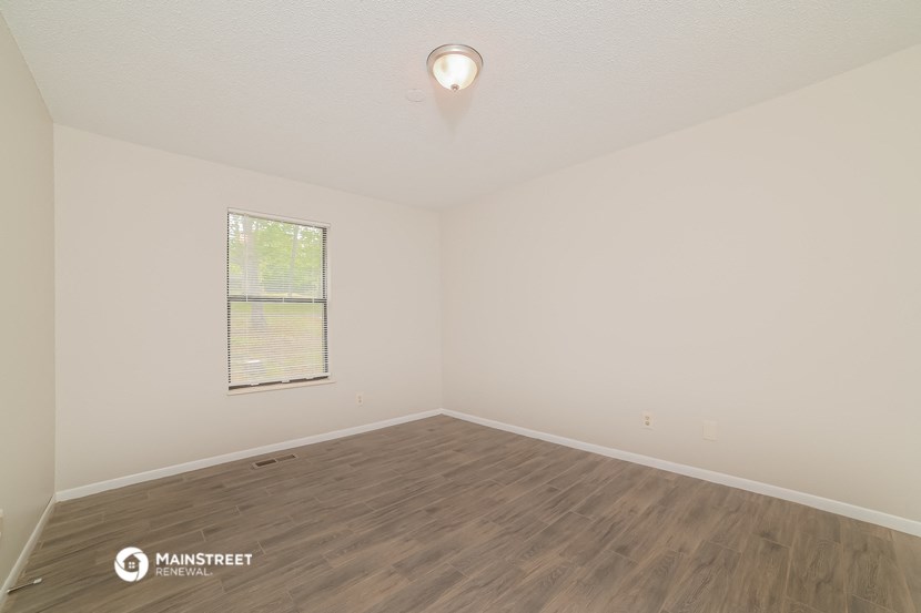 the spacious living room with wood flooring and a window