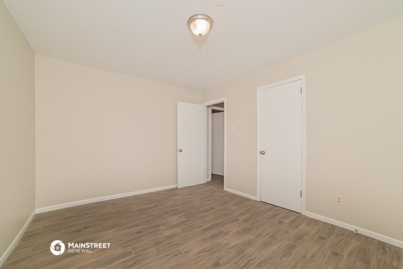 the spacious living room with wood flooring and white walls