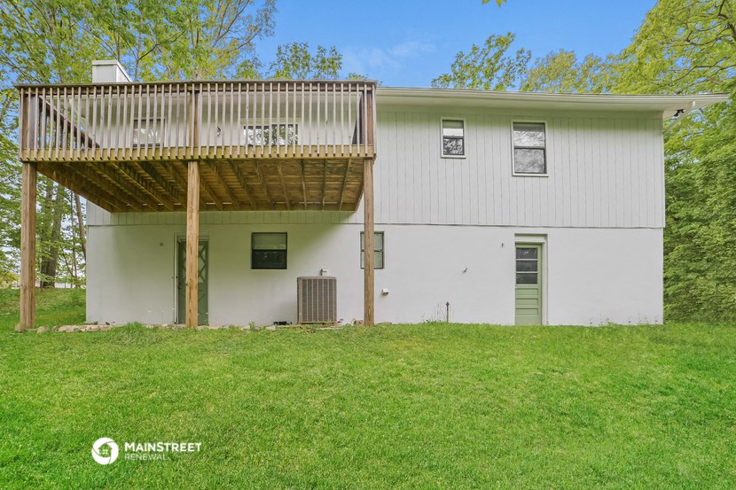a white house with a wooden deck on top of a yard