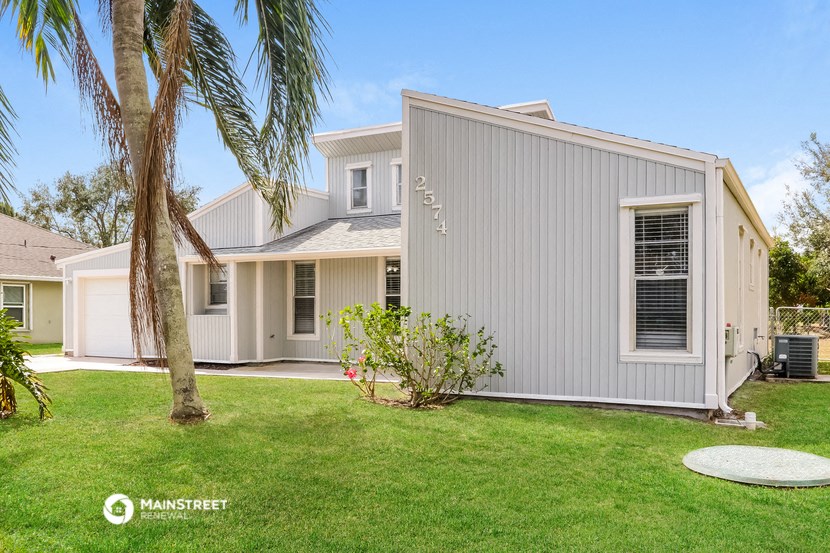 a white house with a yard and a palm tree