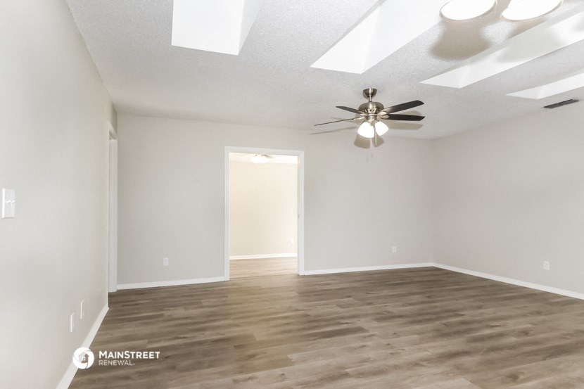 an empty living room with a ceiling fan and white walls