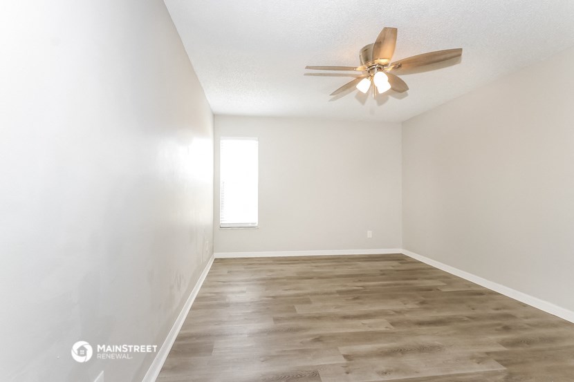 an empty living room with a ceiling fan and white walls