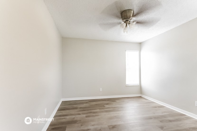 an empty living room with white walls and a ceiling fan