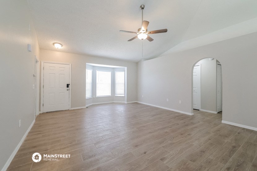 the living room and dining room with a ceiling fan and wood flooring