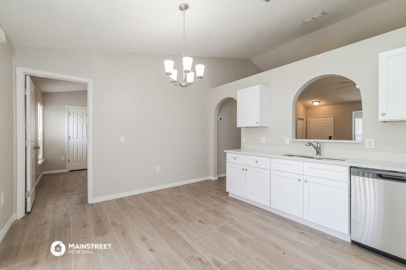 an open kitchen and dining room with white cabinets and counter tops