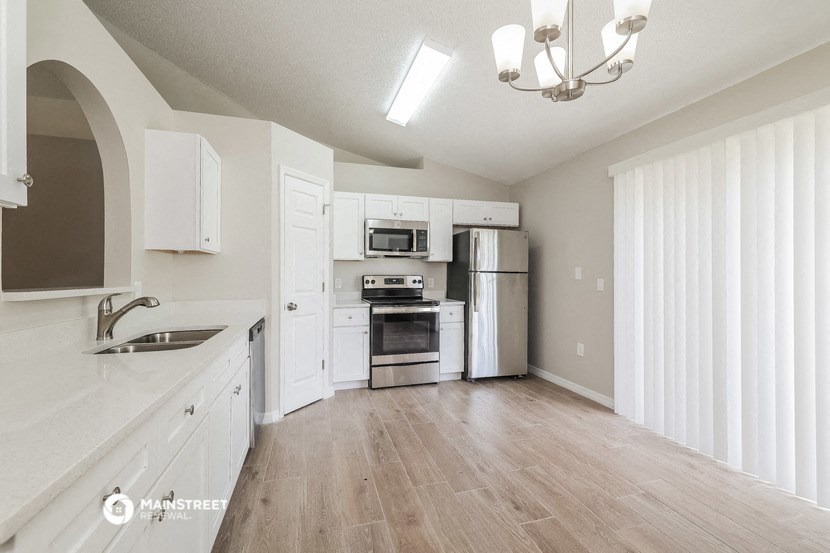 an empty kitchen with white cabinets and stainless steel appliances