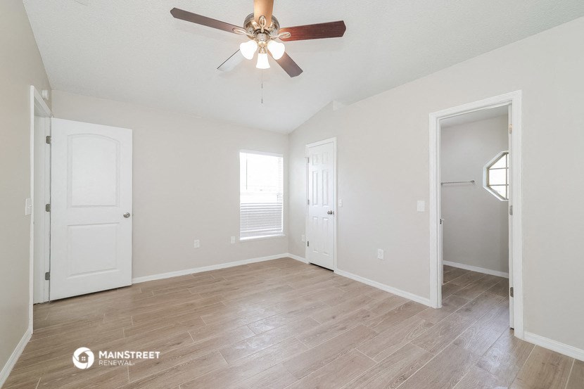 an empty living room with a ceiling fan and a closet