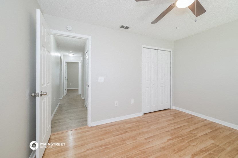 the living room and hallway of an empty house with wood flooring