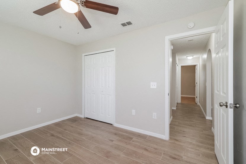 the living room and hallway of an empty house with a ceiling fan