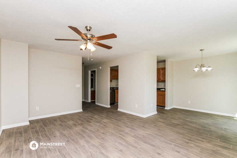 an empty living room with a ceiling fan and wood flooring