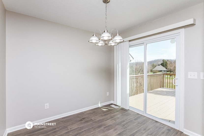 an empty living room with a sliding glass door to a balcony