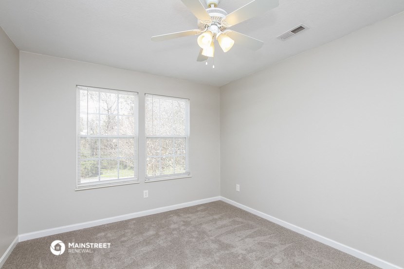 an empty room with a ceiling fan and a window