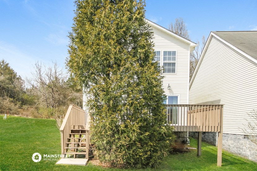 a tree in front of a house with a deck