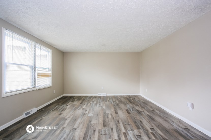 the spacious living room with wood flooring and a large window