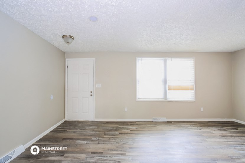 an empty living room with wood floors and a white door and window
