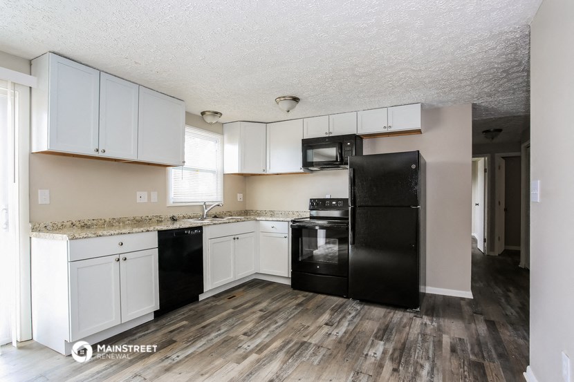 a kitchen with white cabinets and a black refrigerator